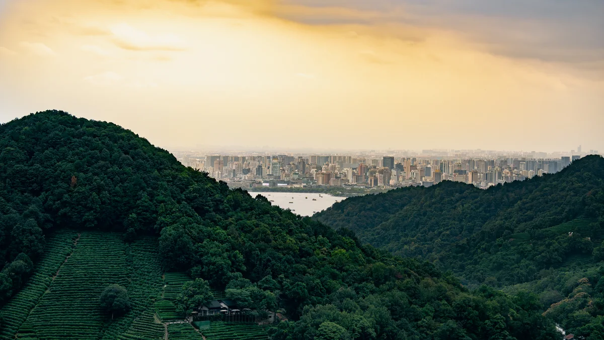 绿色山峦之间远望夕照下的城市